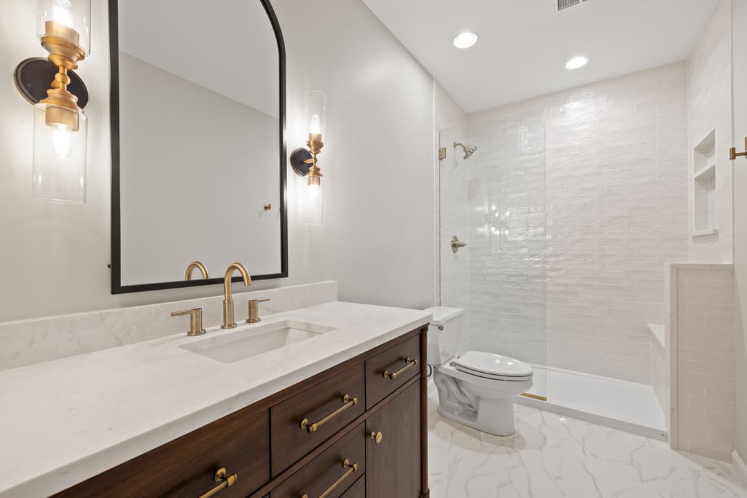 Modern bathroom with elegant fixtures, marble countertop, and sleek walk-in shower.
