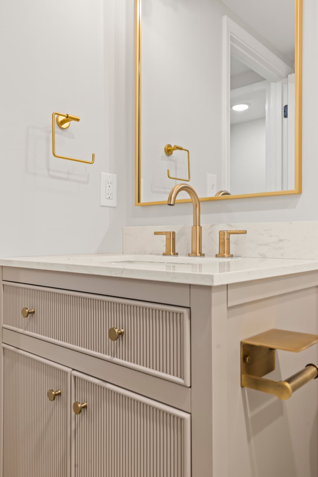 Modern bathroom with gold fixtures, marble countertop, and stylish cabinetry.