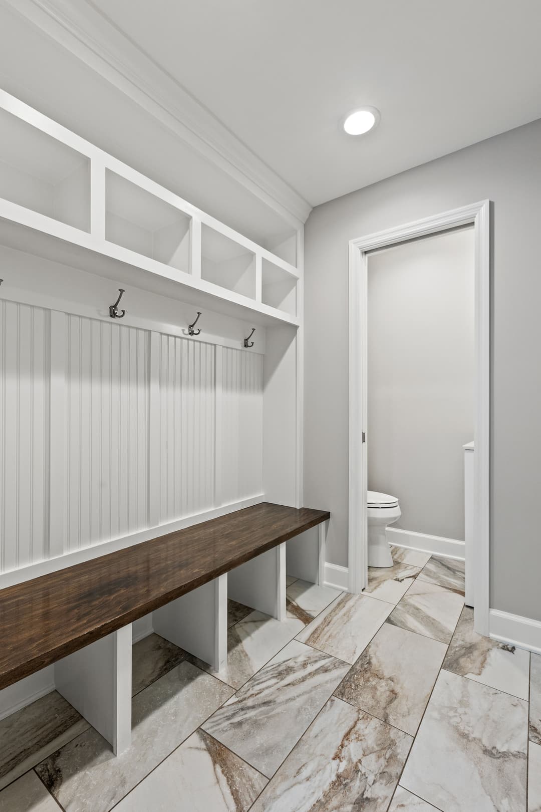 Stylish mudroom with bench seating, storage hooks, and modern tile flooring.