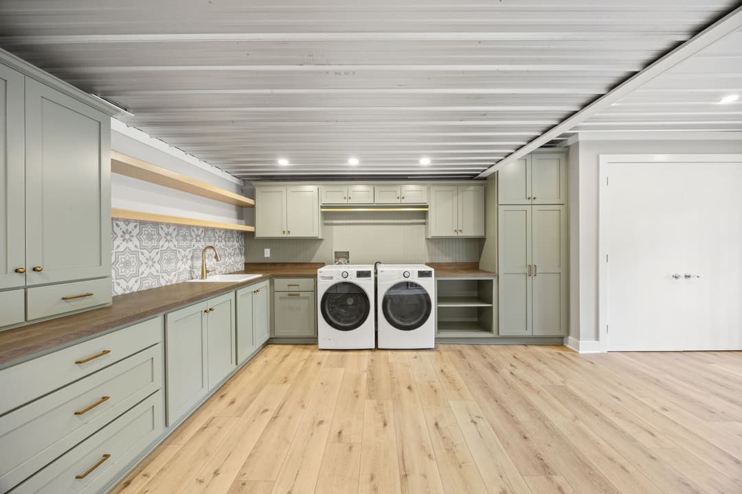 Bright laundry room with modern cabinets, styled backsplash, and new washer-dryer set.