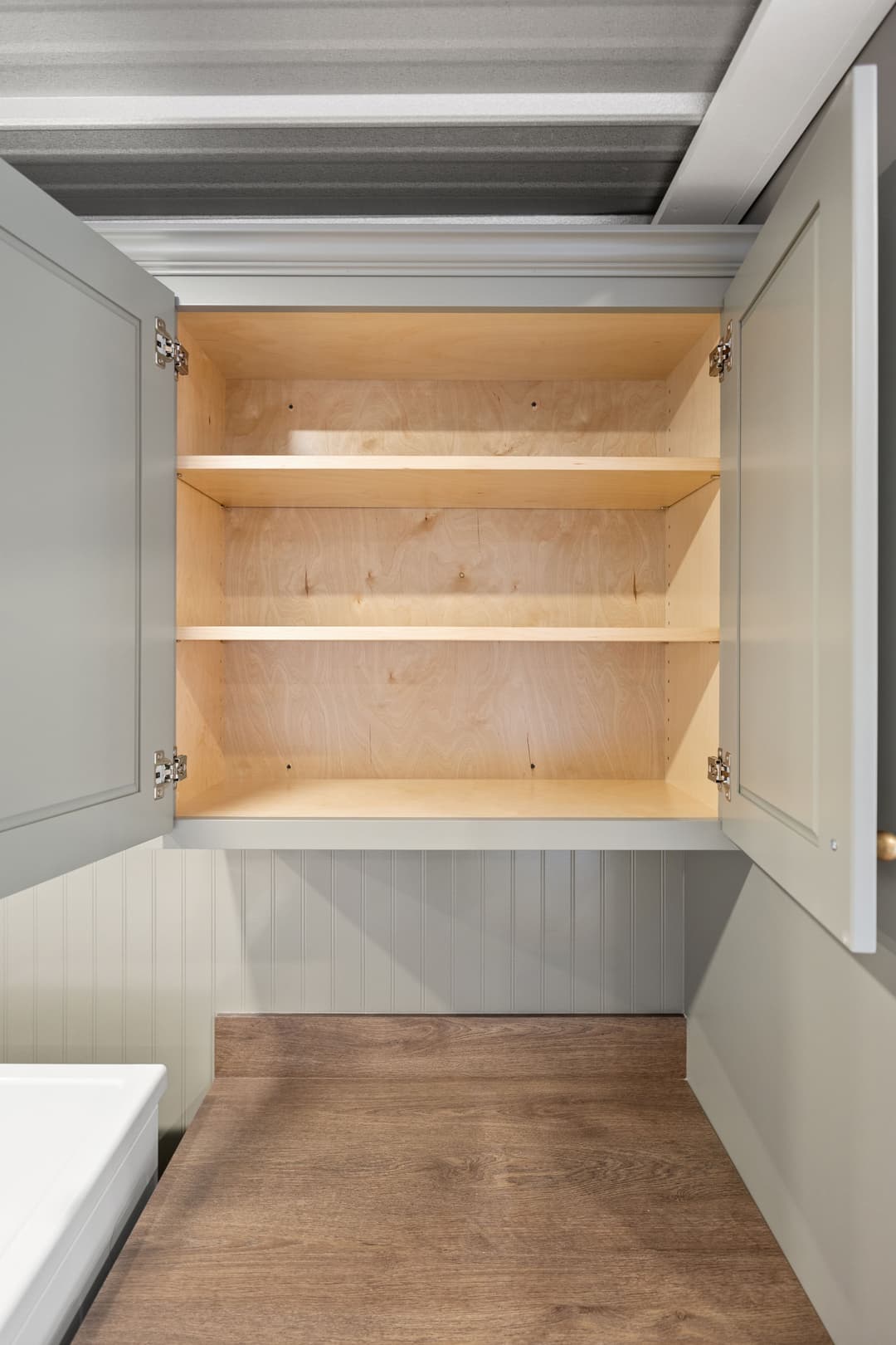 Interior of a gray kitchen cabinet with empty wooden shelves and a wooden countertop.